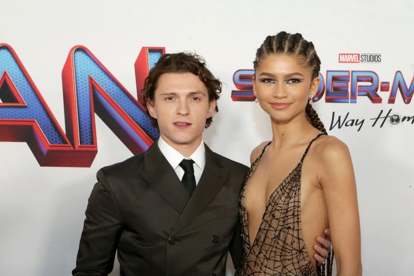 A man in a black suit posing with a woman in a spider-web dress