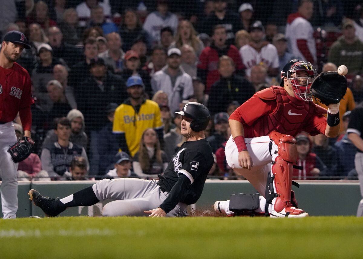 Chicago White Sox's Adam Engel, center, scores ahead of a throw to Boston Red Sox catcher Kevin Plawecki, right, on a sacrifice fly by Reese McGuire during the eighth inning of a baseball game at Fenway Park, Friday, May 6, 2022, in Boston. (AP Photo/Mary Schwalm)