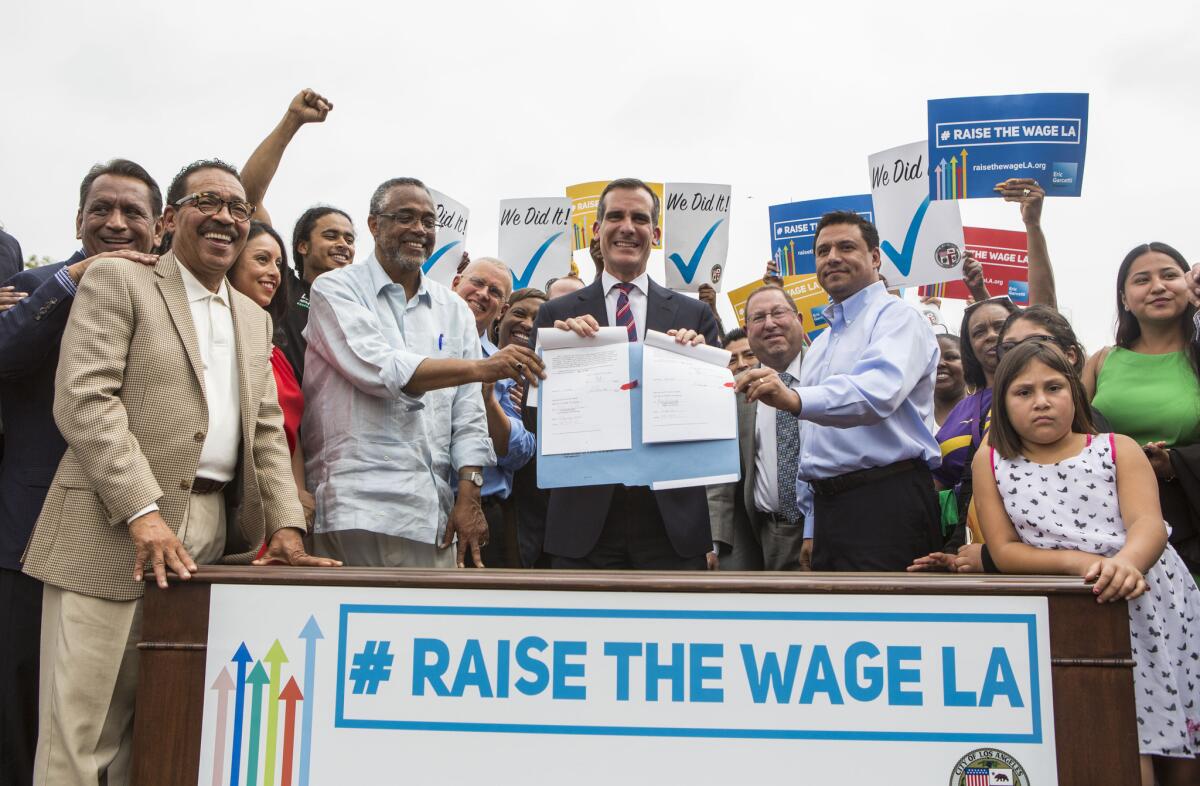 Los Angeles Mayor Eric Garcetti, center, joins members of the City Council and community leaders in a photo after he signed into law an ordinance that will gradually raise the minimum wage to $15 an hour by 2020, in at Martin Luther King Jr. Park in Los Angeles, Saturday, June 13, 2015. The ordinance makes Los Angeles the largest city in the U.S. to gradually raise the minimum wage to $15 an hour.