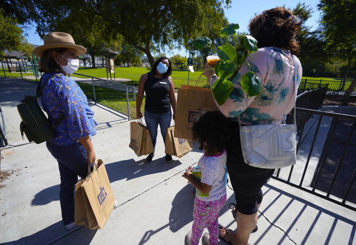 Sandra Mendoza and Elizabeth Castro canvas a local park offering information and hand bags filled with various items.