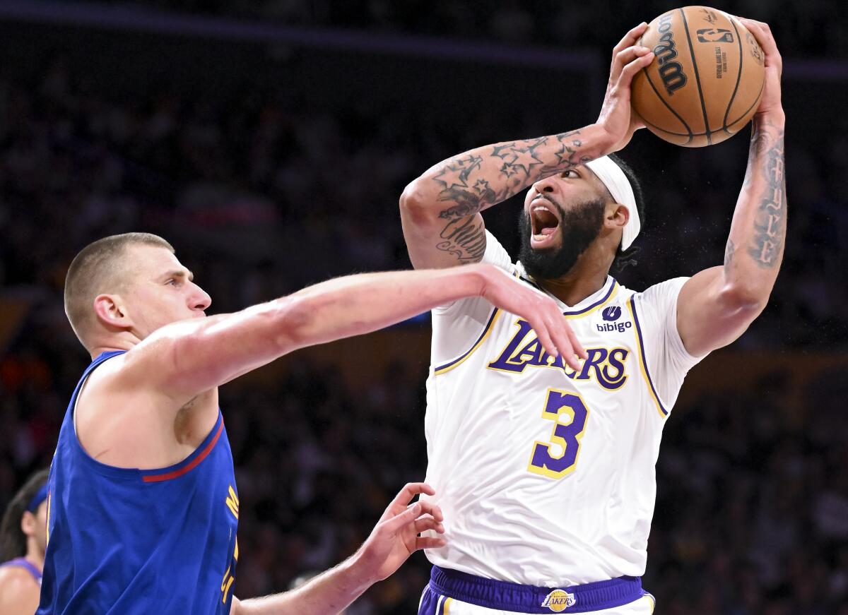 Lakers forward Anthony Davis, right, goes up for a shot while defended by Nuggets center Nikola Jokic.