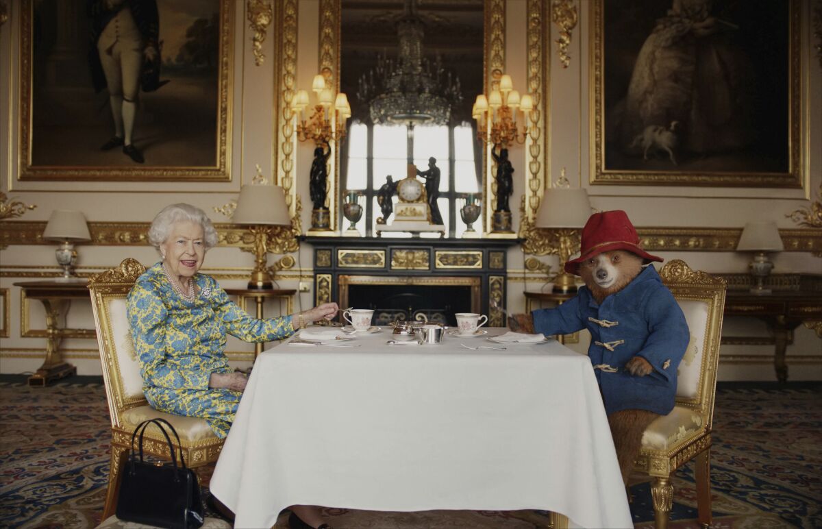In this undated photo provided by Buckingham Palace/ Studio Canal / BBC Studios / Heyday Films on Saturday, June 4, 2022, Queen Elizabeth II and Paddington Bear have cream tea at Buckingham Palace, in London, taken from a film that was shown at the BBC Platinum Party at the Palace. (Buckingham Palace/ Studio Canal / BBC Studios / Heyday Films via AP)