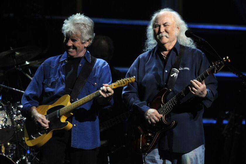 Two elderly men each playing a guitar on a stage