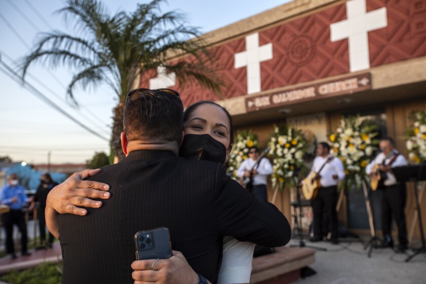 A man and woman hug after a wake for Tom Rivera.