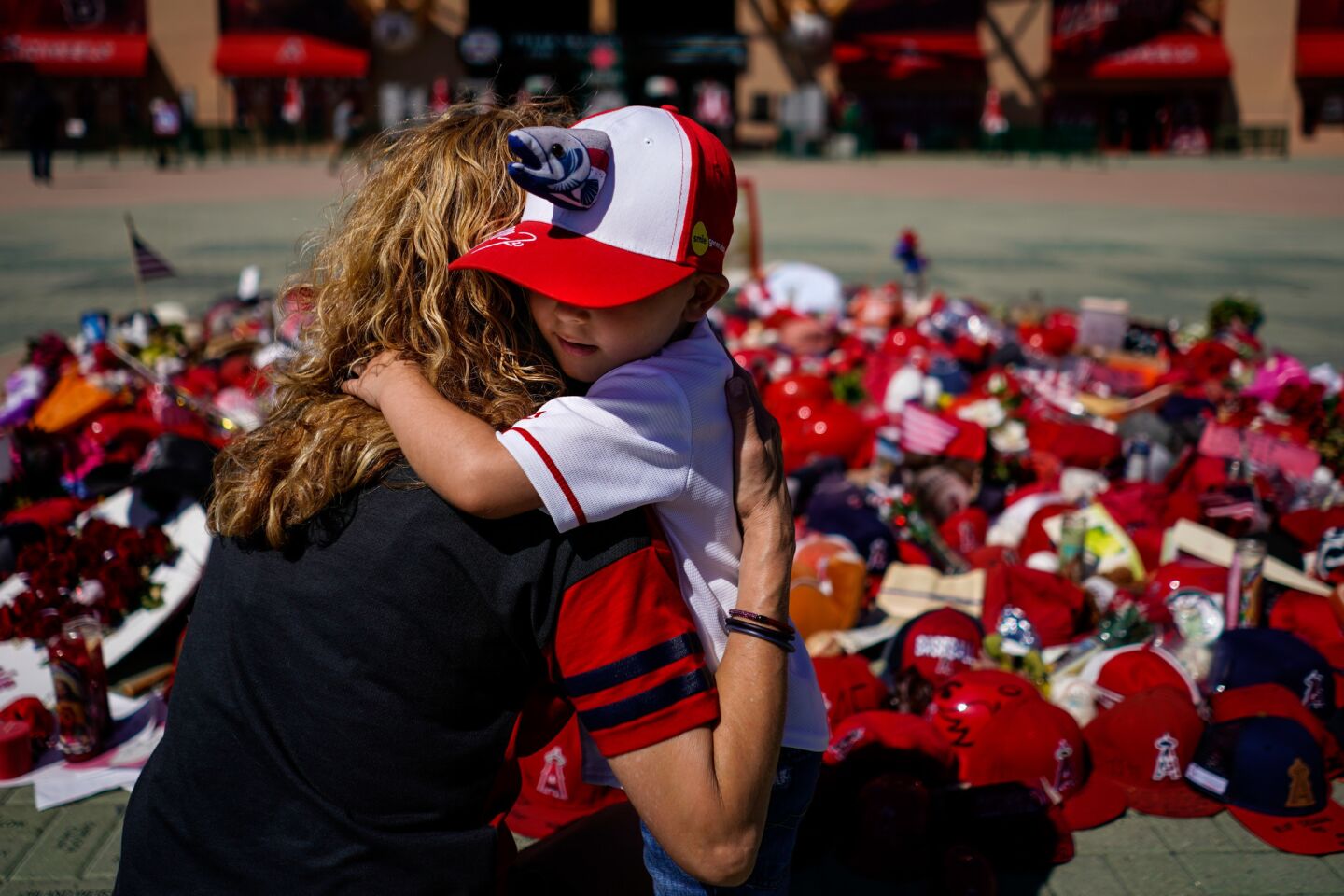 Julian Segura, 3, hugs his mom, Sylvia Menchaca, of the San Fernando Valley, in front of a memorial for Tyler Skaggs, after Julian placed a helmet with a message to the late Angels pitcher.