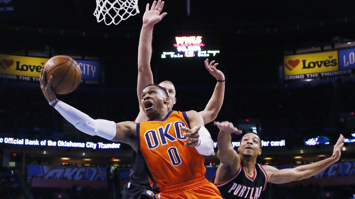 Thunder guard Russell Westbrook attempts a reverse layup against Trail Blazers center Mason Plumlee and guard C.J. McCollum, right, during the first quarter Sunday.