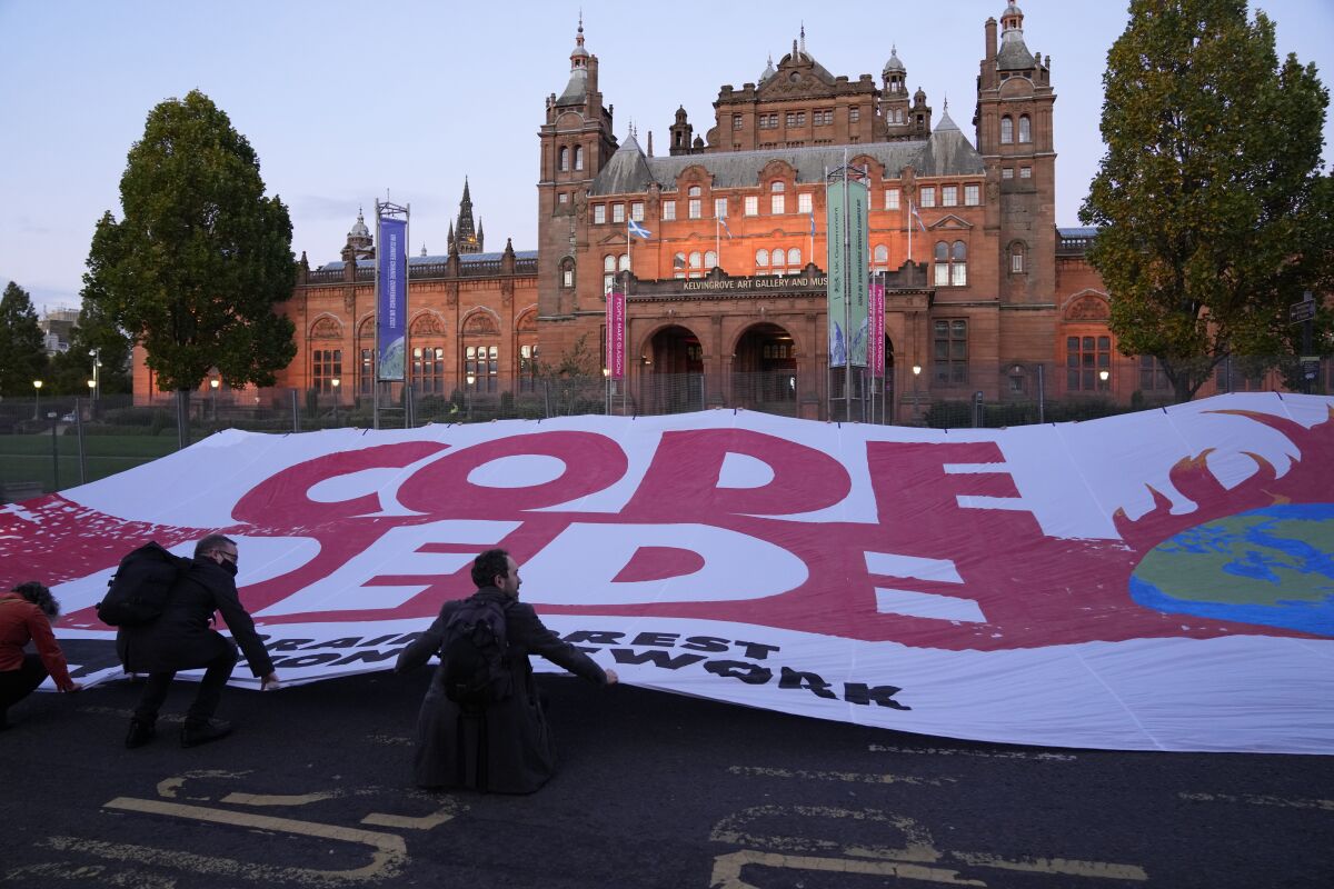 Climate activists unfurl a large banner reading "Code Red" across the street outside the Kelvingrove Art Gallery and Museum as the COP26 U.N. Climate Summit takes place in Glasgow, Scotland, Wednesday, Nov. 3, 2021. (AP Photo/Alastair Grant)