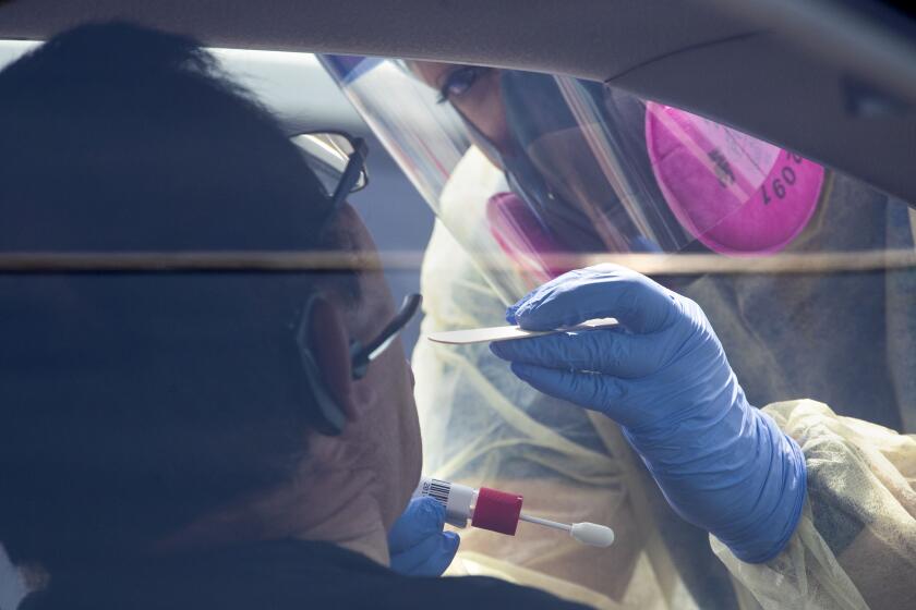 BOYLE HEIGHTS, CA - APRIL 29: AltaMed Health Services staff swabs a patient during COVID-19 testing on Wednesday, April 29, 2020 in Boyle Heights, CA. (Brian van der Brug / Los Angeles Times)