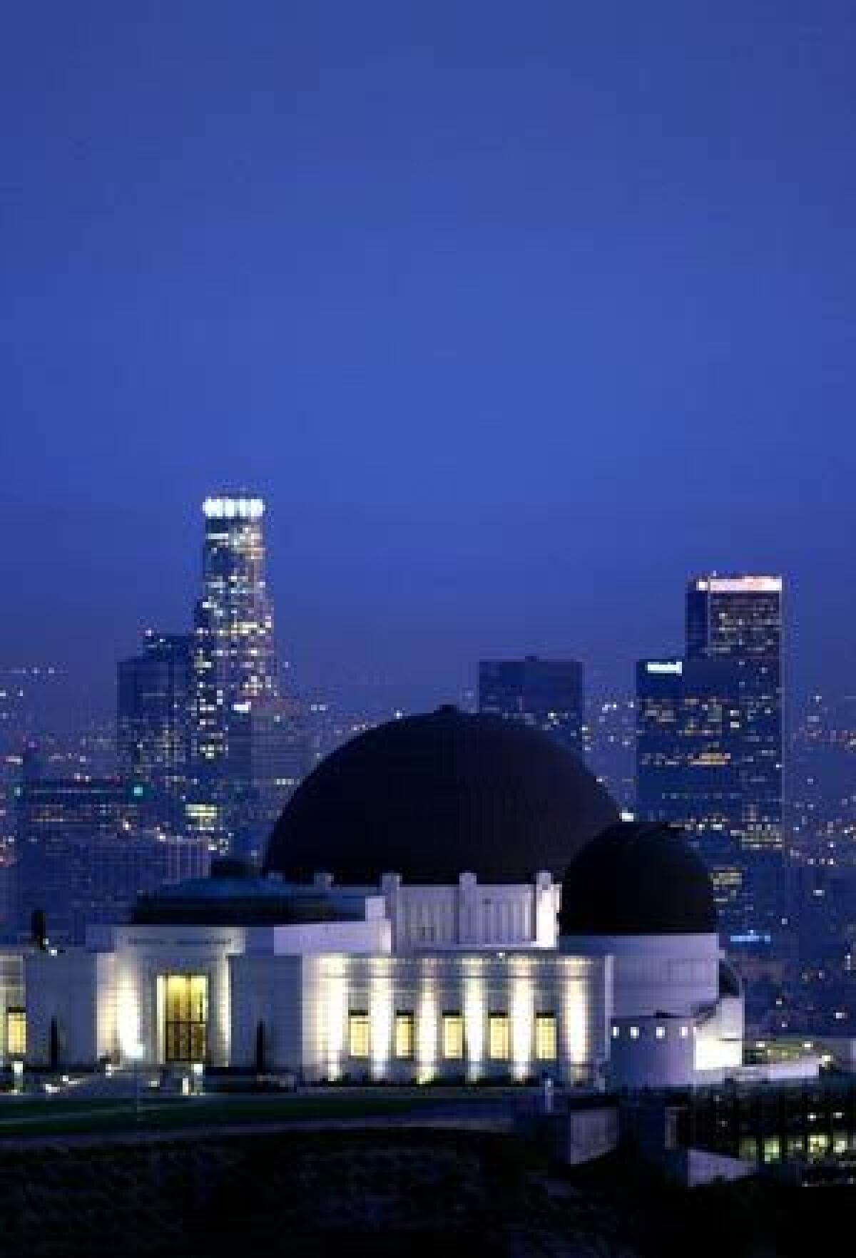 The Griffith Observatory at night with downtown Los Angeles in the background.