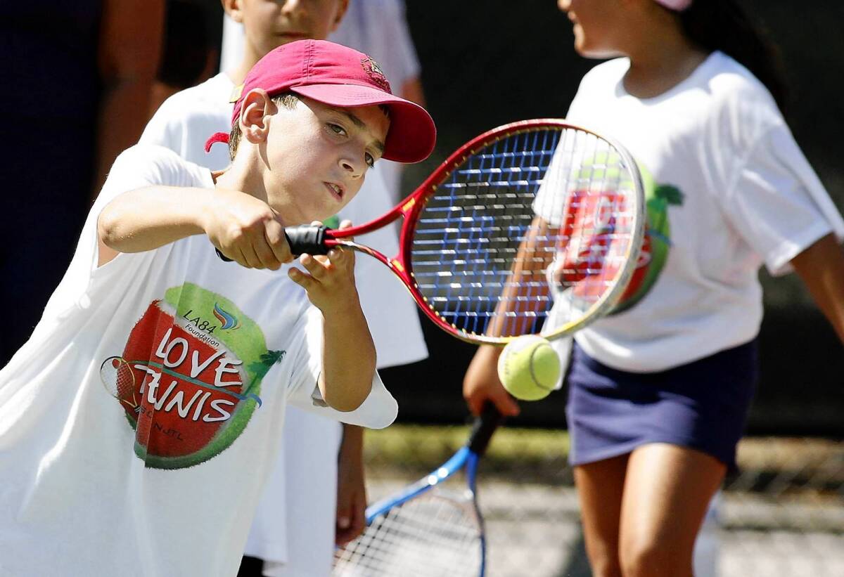 Anthony Majinian leans over to hit the tennis ball during a six-week fundamental camp put on by Ron Zambrano at Fremont Tennis Center.
