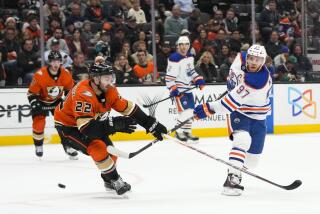Edmonton Oilers' Connor McDavid (97) hits the puck under pressure from Anaheim Ducks' Kevin Shattenkirk (22) during the second period of an NHL hockey game Wednesday, Jan. 11, 2023, in Anaheim, Calif. (AP Photo/Jae C. Hong)