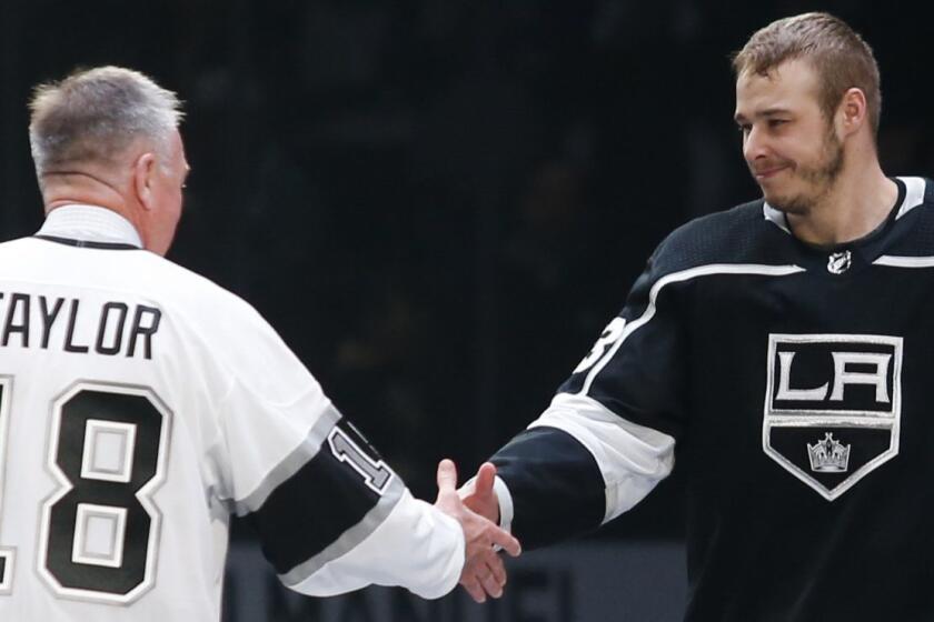 Los Angeles Kings forward Dustin Brown (23) shakes hands with Hockey Hall of Fame Dave Taylor prior to the NHL hockey game between Los Angeles Kings and Calgary Flames Monday, April 1, 2019, in Los Angeles. Brown was honored for becoming the Kings franchise leader in games played last week. (AP Photo/Ringo H.W. Chiu)