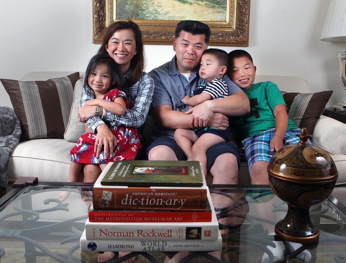 Susannah Kim, holding her 4-year-old daughter Noelle, with her husband Jonathan, and two sons Peter, 2, and Ethan, 10, in their home in La Canada Flintridge on Tuesday, October 22, 2013. Susannah, who works full time in marketing, won the "Courage to Dream" award from Little Pink Book.
