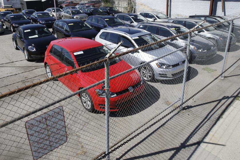 Volkswagen diesels are shown behind a security fence on a storage lot near a VW dealership in Salt Lake City.