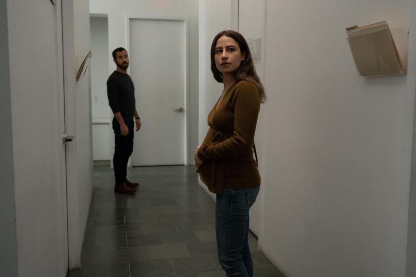 A man and a pregnant woman stand in a hallway.