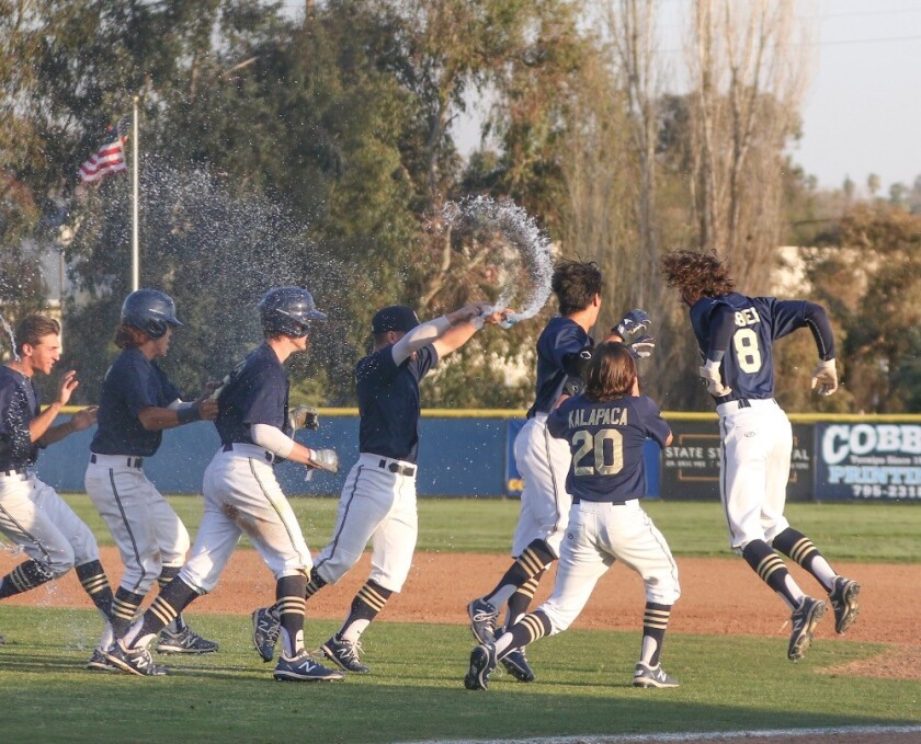Yucaipa baseball players run on the field and jump and spray water.