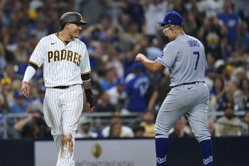 San Diego Padres' Manny Machado, left, jokes with Los Angeles Dodgers starting pitcher Julio Urias during the sixth inning of a baseball game Wednesday, Sept. 28, 2022, in San Diego. (AP Photo/Gregory Bull)