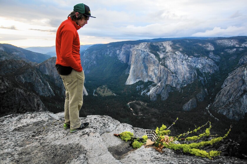 Max Buchini stands next to a heart-shaped rock with feather wings in Yosemite National Park, meant as a memorial to the late BASE jumpers Dean Potter and Graham Hunt. Buchini credits Potter for inspiring his love of rock climbing.