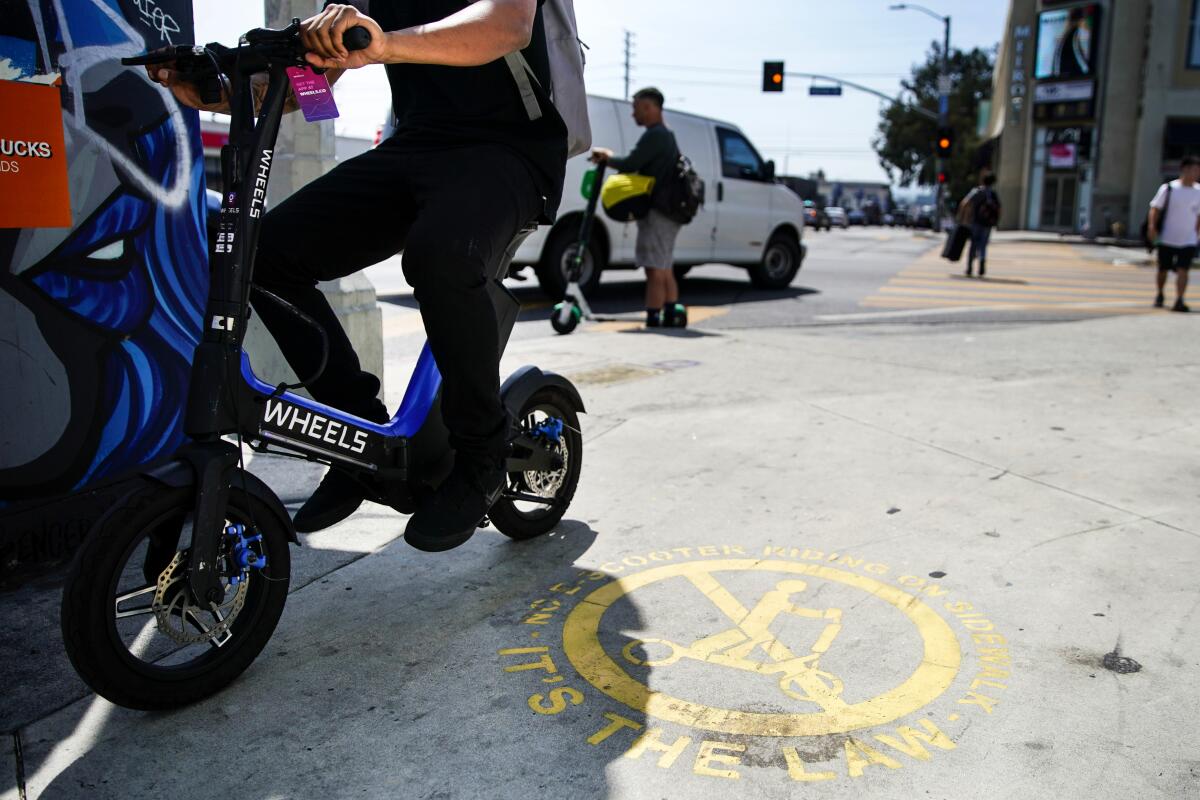 A painted sign reminds scooter operators and pedestrians that electric scooters aren't allowed to be operated on sidewalks.