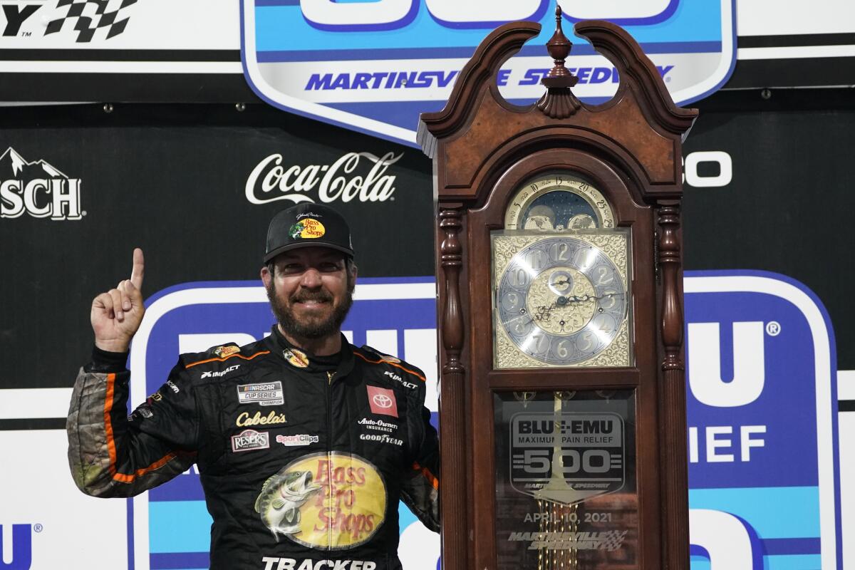 Martin Truex Jr. (19) celebrates with the winners' trophy after winning the NASCAR Cup Series auto race at Martinsville Speedway in Martinsville, Va., Sunday, April 11, 2021. (AP Photo/Steve Helber)