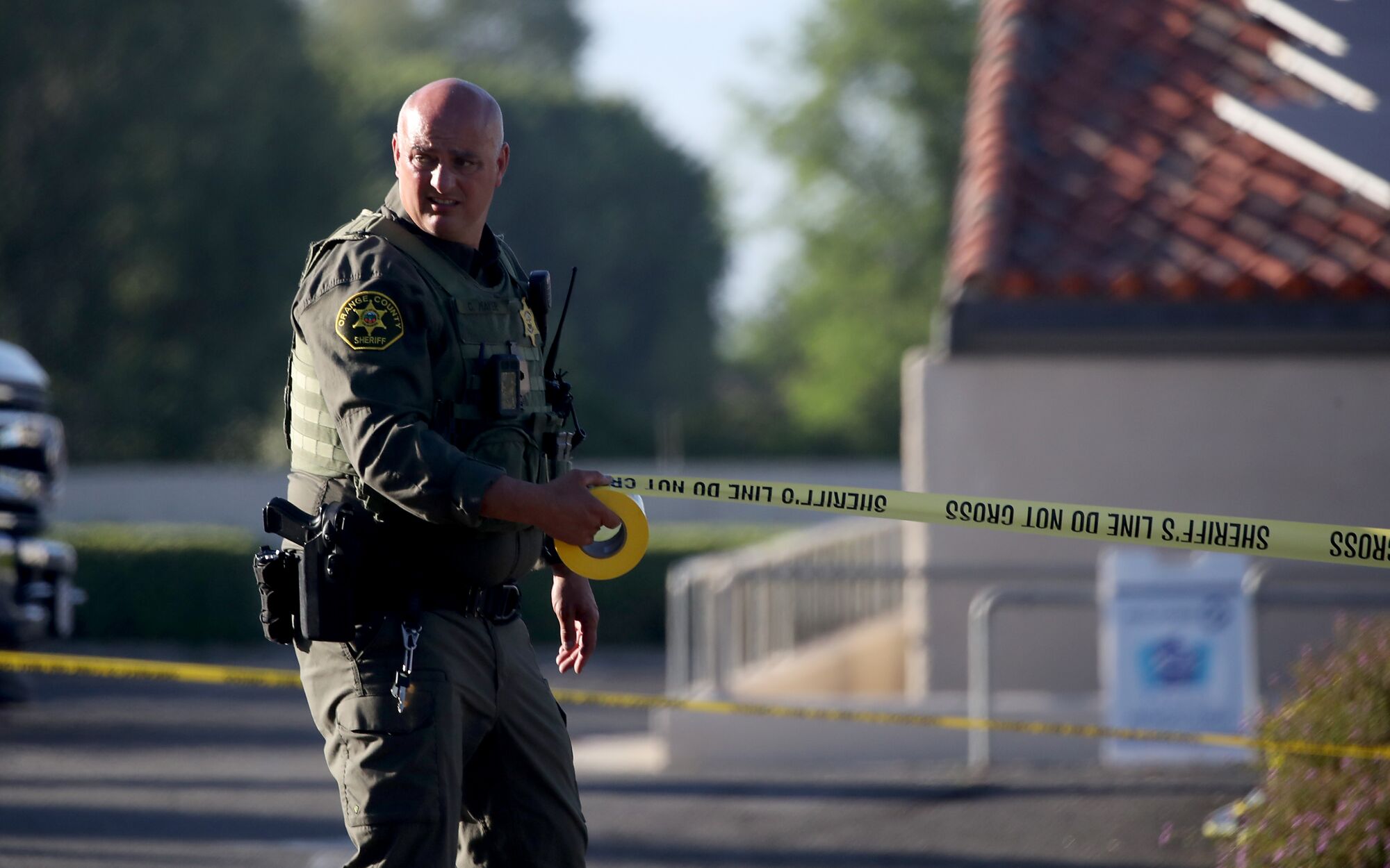 An Orange County sheriff's deputy unspooling yellow police tape