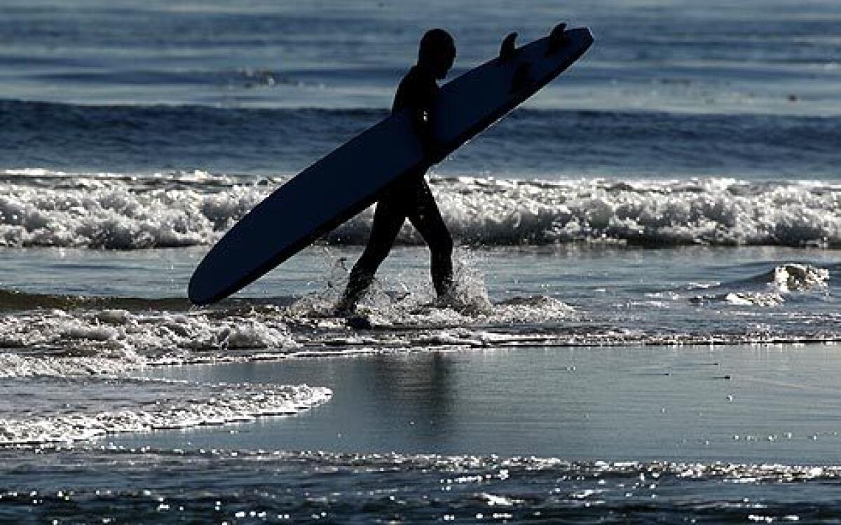A surfer emerges from the water at Surfrider Beach in Malibu. The perfectly shaped point break lures wave riders from around the world. But the chronically polluted water has given countless swimmers and surfers queasy stomachs, eye infections and nasty rashes.