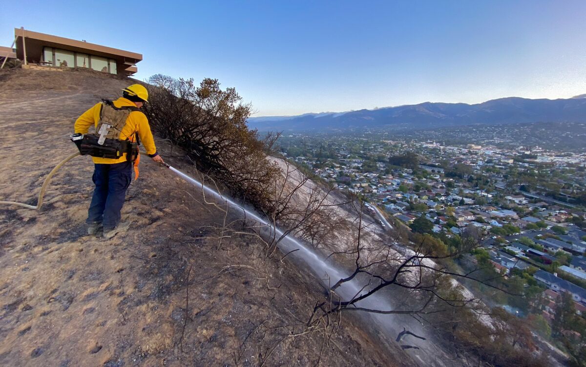A firefighter sprays a scorched hillside above Santa Barbara.