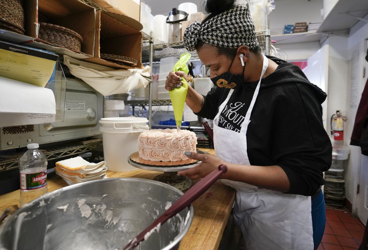 Carleen Anderson, lead cake decorator at Twiggs Bakery & Coffeehouse, adds finishing touches to a strawberry and cream cake.