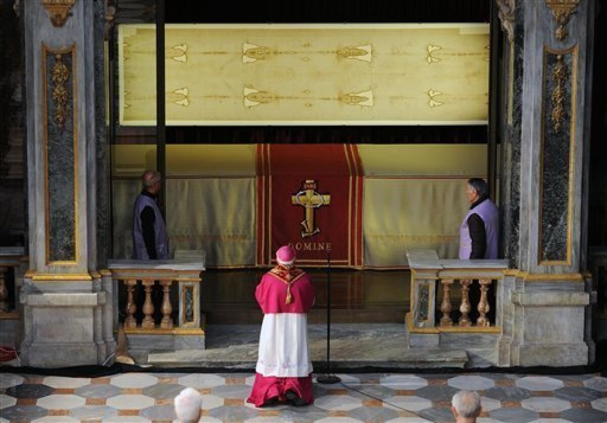 Archbishop of Turin Cesare Nosiglia, center, kneels in front of the Shroud of Turin that went on display for a special TV appearance Saturday, March 30, 2013. The Shroud went on display amid new research disputing claims it's a medieval fake and purporting to date the linen some say was Jesus' burial cloth to around the time of his death. Pope Francis sent a special video message to the event in Turin's cathedral, but made no claim that the image on the shroud of a man with wounds similar to tho
