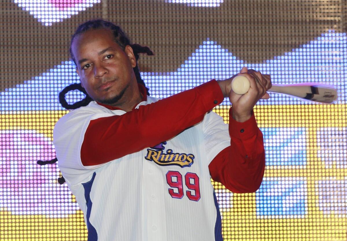 Former MLB star Manny Ramirez poses with an honorary baseball bat and new team jersey Tuesday after signing a short-term contract to play on the EDA Rhinos in Taiwan's professional baseball league.