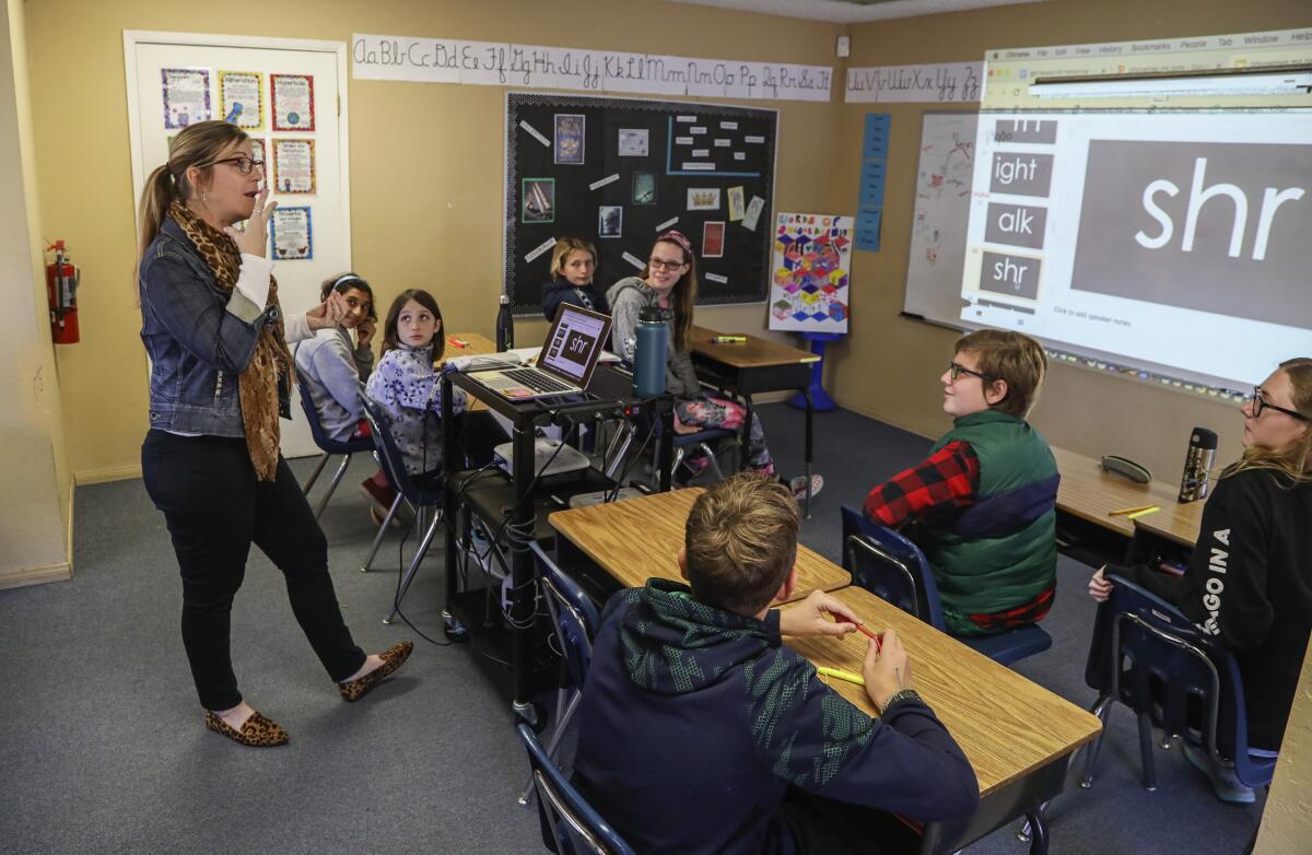 A teacher works with middle school students on a phonics lesson at a school that caters to kids with dyslexia