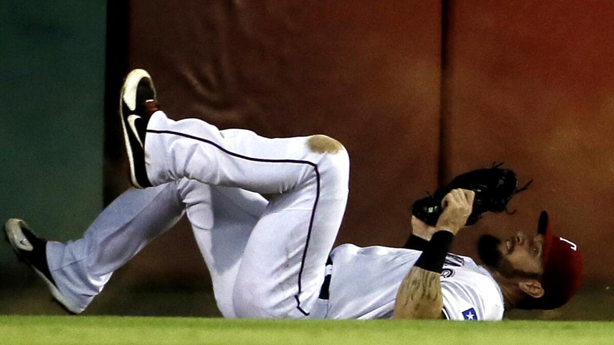 Rangers left fielder Josh Hamilton tumbles to the warning track after making a catch on a ball hit by the Angels' Shane Victorino and crashing into the wall in the second inning Thursday night.