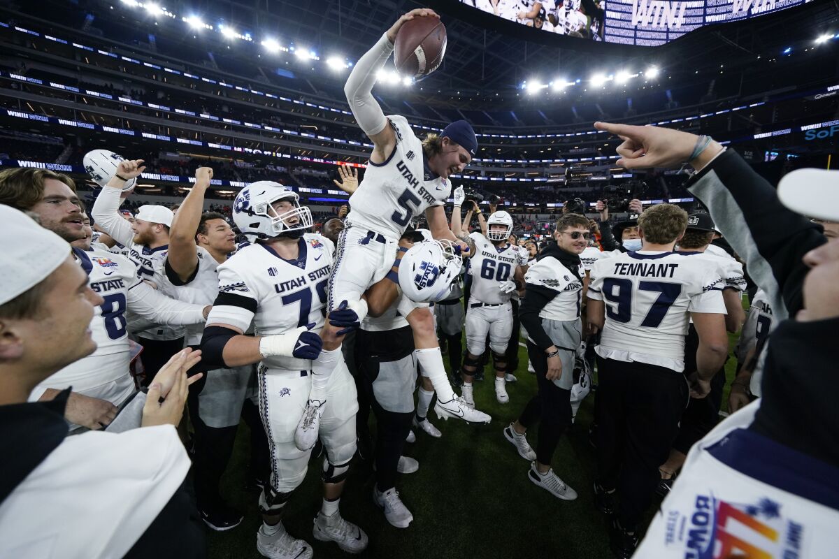 Utah State quarterback Cooper Legas (5) is hoisted on the shoulders of his teammates after the Aggies won the LA Bowl.