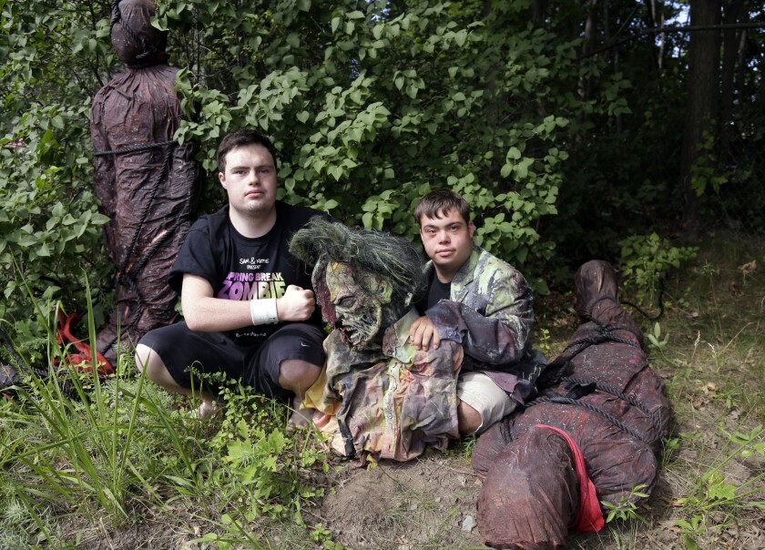FILE - In this July 12, 2016, file photo, Sam Suchmann, left, and Mattie Zufelt pose with ghoulish figures at Sam's home in Providence, R.I. The two young men who caused a sensation four years ago when they created their own gory zombie movie are back, this time in a documentary championed by a Hollywood luminary that chronicles their tenacious, years-long effort to see their silver screen dream come to fruition. "Sam & Mattie Make a Zombie Movie," was released Tuesday, April 6, 2021, on Apple TV. (AP Photo/Elise Amendola, File)