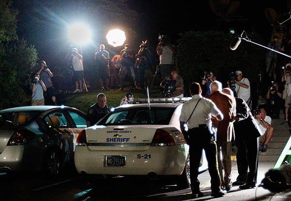 A handcuffed Jerry Sandusky is led into a police car outside Centre County Courthouse after the jury's verdict was announced.