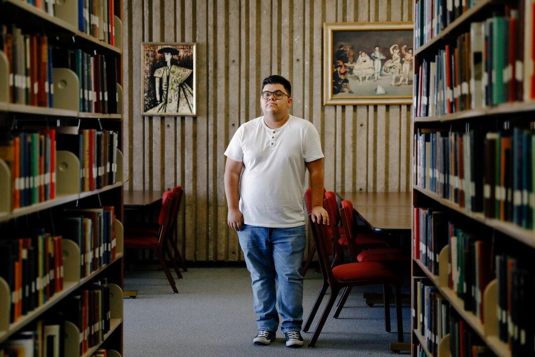 مارک آراوجو-لوینسون، که در حال مطالعه زبان سرانو است، در میان قفسه های کتاب ایستاده است.