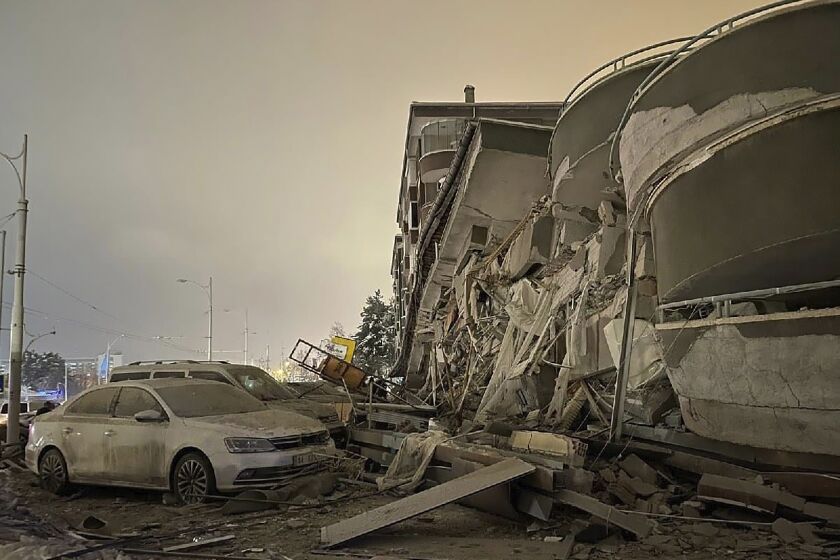 Damaged vehicles sit parked in front of a collapsed building following an earthquake in Diyarbakir, southeastern Turkey, early Monday, Feb. 6, 2023. A powerful quake has knocked down multiple buildings in southeast Turkey and Syria and many casualties are feared. (Depo Photos via AP)