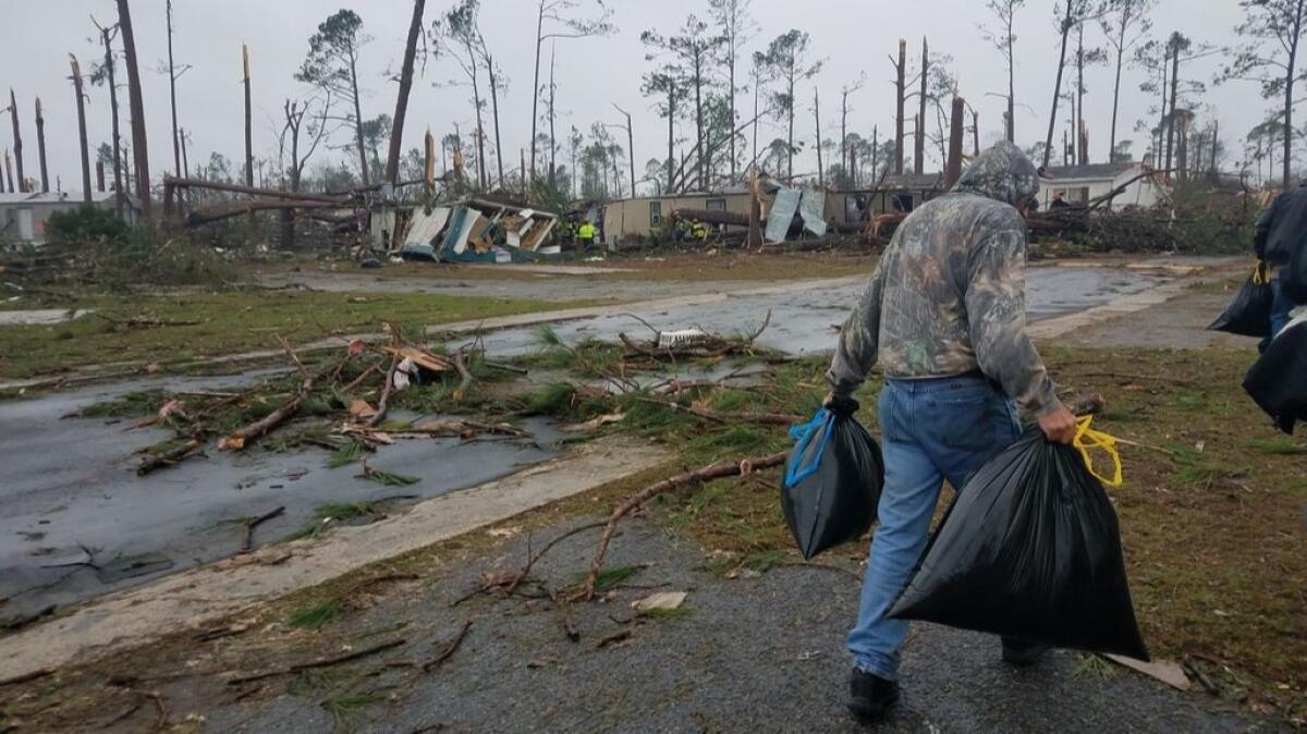 Nathan Mahan carries clothes from his destroyed home.