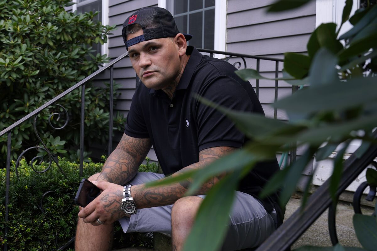 Mike Gilpatrick, who as a teenager was incarcerated at the Youth Development Center, poses on the front steps of his home, Wednesday, Sept. 8, 2021, in Nashua, N.H. Gilpatrick, 38, filed a lawsuit Monday Sept. 13, alleging he was physically and sexually abused at the former Youth Development Center in Manchester, which has been the target of a criminal investigation since 2019 and is slated to close in 2023. (AP Photo/Charles Krupa)