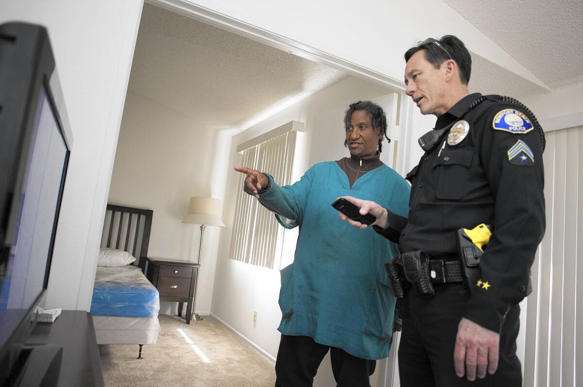 Homeless liaison officer Tony Yim of the Newport Beach Police Department tries to help Toni Horn, 61, get the television working at her new apartment in Lake Forest on Tuesday. Horn spent years on the streets in Newport Beach before getting the apartment with help from Yim.