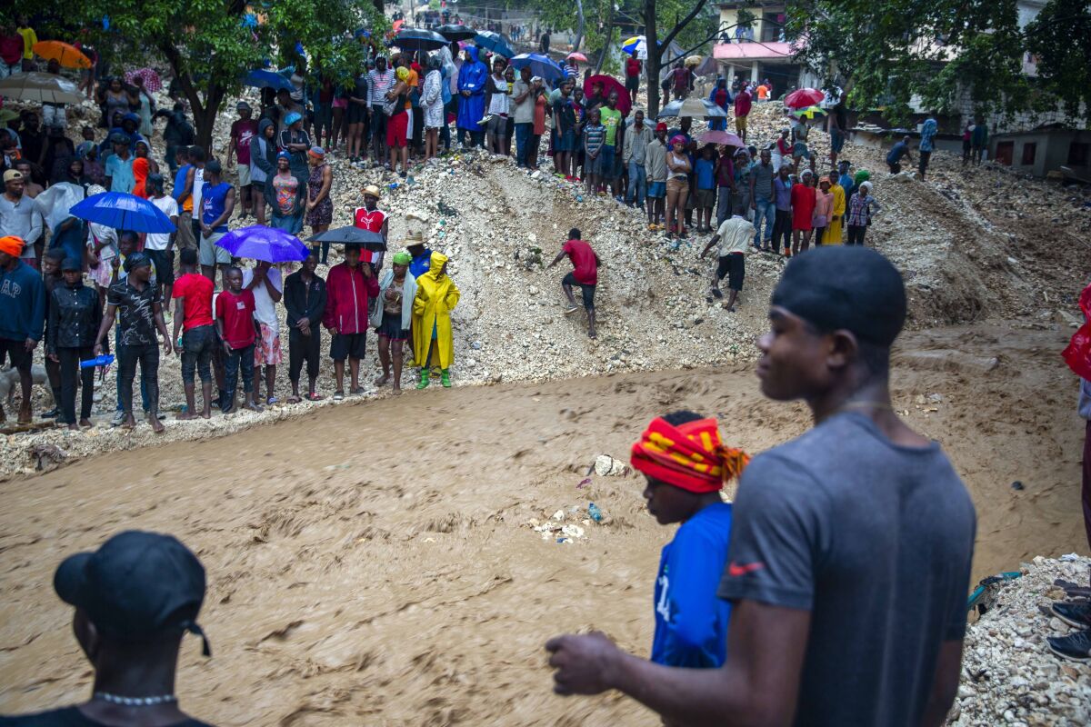 Locals stand on the banks of the Tet Dlo River during the passing of Tropical Storm Laura in Port-au-Prince, Haiti. 