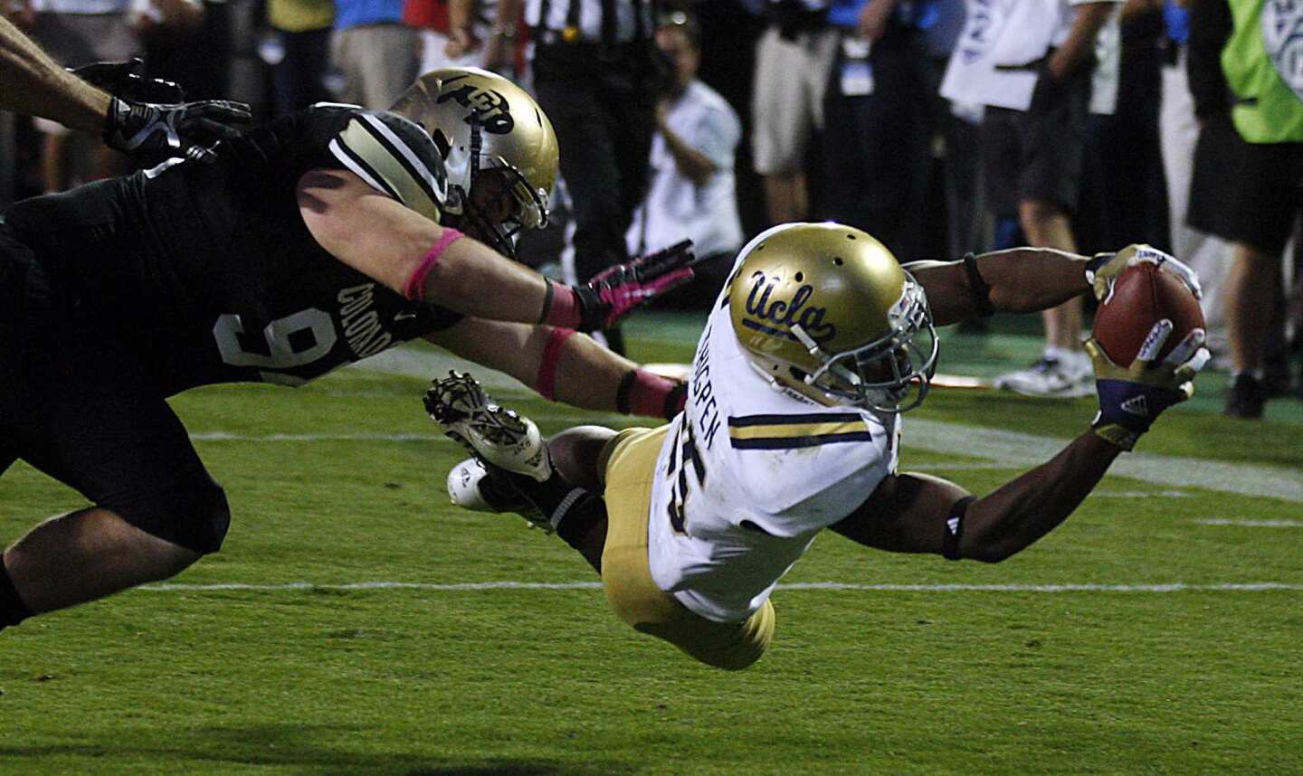 UCLA receiver Damien Thigpen dvies into the end zone past Colorado defensive lineman Tyler Henington for a touchdown in the fourth quarter Saturday. Thigpen scored on a reverse.