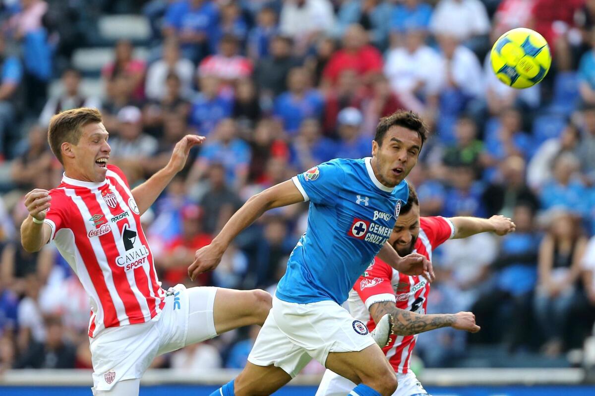 El jugador de Cruz Azul, Omar Mendoza, disputa el balón con Claudio Riaño y con Luis Gallegos, del Necaxa, durante el partido de la jornada inicial del Torneo Clausura del fútbol mexicano realizado en el Estadio Azul, en Ciudad de México.