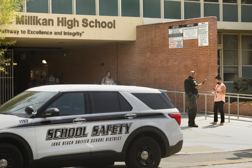 Long Beach, California-Sept 29, 2021-A Long Beach Unified School District officer speaks to a woman outside Robert A. Millikan High School in Long Beach on Sept. 29, 2021. (Carolyn Cole / Los Angeles Times)