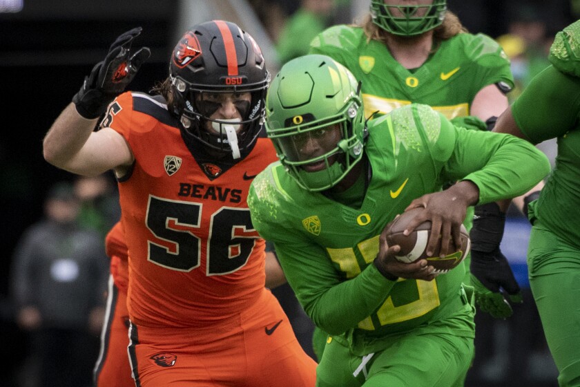 Oregon quarterback Anthony Brown (13) tries to elude the tackle of Oregon State linebacker Riley Sharp (56) during the second quarter of an NCAA college football game Saturday, Nov. 27, 2021, in Eugene, Ore. (AP Photo/Andy Nelson)