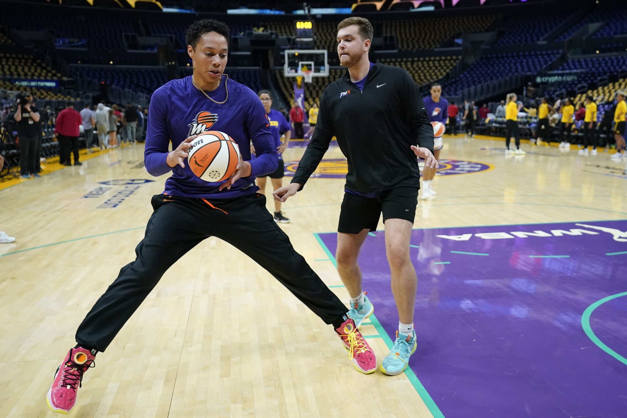 Phoenix Mercury center Brittney Griner holds the basketball while a staff member guards her during her pregame warm-up