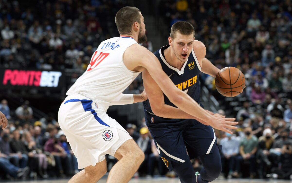 Denver Nuggets center Nikola Jokic, right, drives the lane as Los Angeles Clippers center Ivica Zubac defends in the first half of an NBA basketball game Wednesday, Jan. 19, 2022, in Denver. (AP Photo/David Zalubowski)