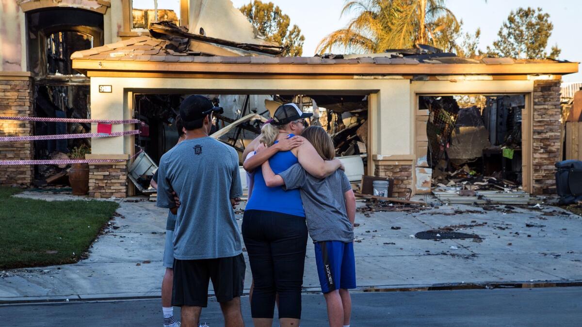 Neighbors console each other in front of a home that burned in Anaheim Hills.