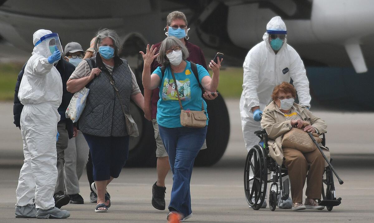 A woman gestures as medical personnel help load passengers from the Grand Princess cruise ship onto airplanes at Oakland International Airport on Tuesday.