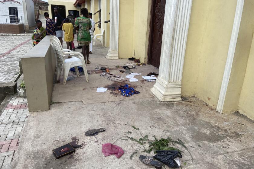 People stand outside the St. Francis Catholic Church in Owo Nigeria, Sunday, June 5, 2022. Lawmakers in southwestern Nigeria say more than 50 people are feared dead after gunmen opened fire and detonated explosives at a church. Ogunmolasuyi Oluwole with the Ondo State House of Assembly said the gunmen targeted the St Francis Catholic Church in Ondo state on Sunday morning just as the worshippers gathered for the weekly Mass. (AP Photo/Rahaman A Yusuf)